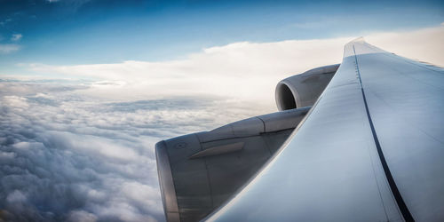 Cropped image of airplane wing over cloudscape