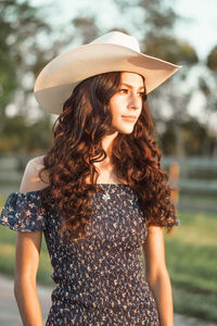 Portrait of young woman standing against trees