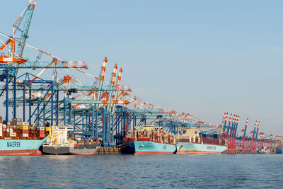 Cranes at commercial dock against clear sky