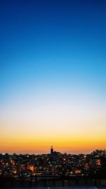 Illuminated buildings against clear sky at sunset