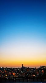 Illuminated buildings against clear sky at sunset