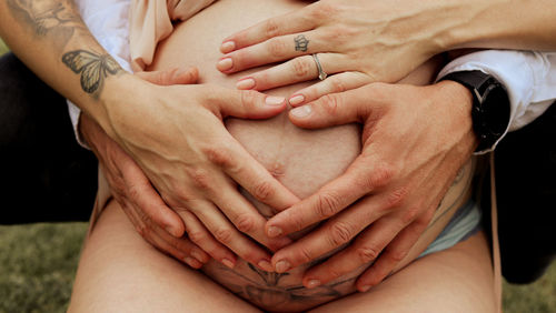 Cropped image of woman holding hands on your baby belly 