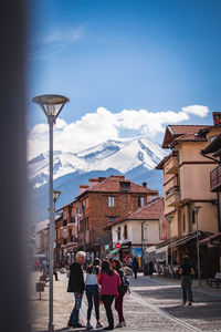 People walking on street amidst buildings in city against mountains