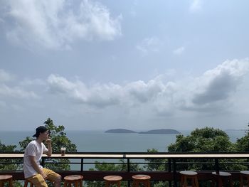Man standing by railing against sky