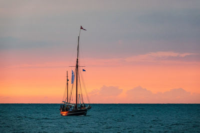 Sailboat sailing on sea against sky during sunset