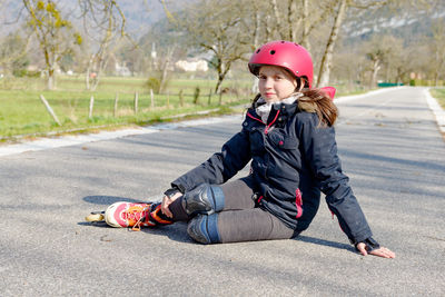 Full length of teenage girl sitting on road