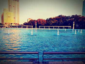 View of swimming pool by river against buildings