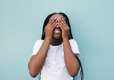 Portrait of young woman standing against blue background