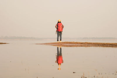 Rear view of man standing on beach against sky