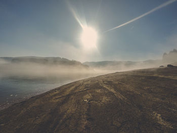 Scenic view of landscape against bright sun