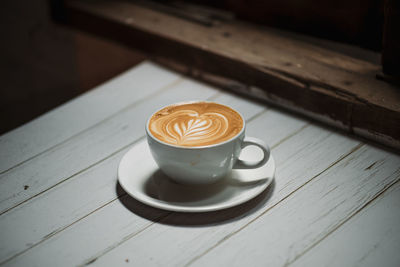 Latte art coffee on wooden table in coffee shop