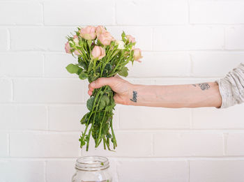 Woman holding flower bouquet against white wall