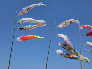 Low angle view of fish shaped decorations against clear blue sky