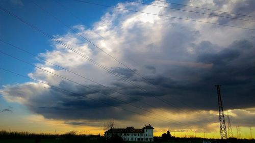 Low angle view of power lines against cloudy sky