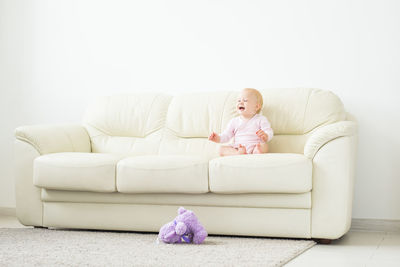 Full length of baby girl sitting on sofa