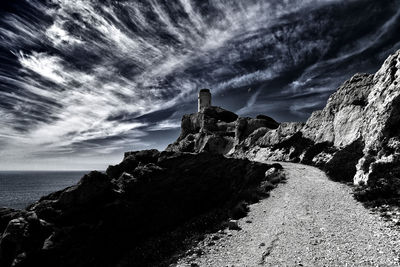 Rock formation on sea shore against sky