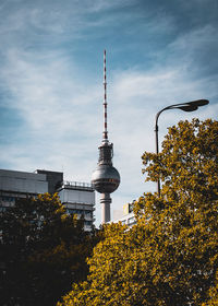 Low angle view of communications tower against cloudy sky