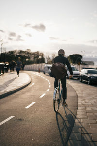 Rear view of man riding bicycle on road