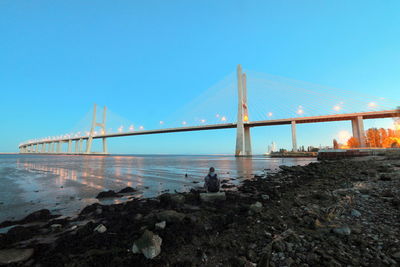 Suspension bridge over sea against clear blue sky