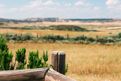 Close-up of wooden post with field in background