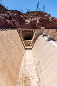 Electricity pylons on rock formation at hoover dam against sky