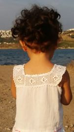 Rear view of woman standing at beach against sky