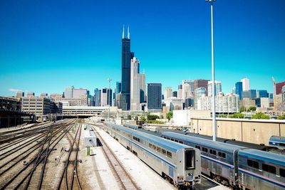 Trains by willis tower and cityscape against sky