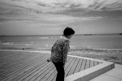 Rear view of woman looking at sea shore against sky