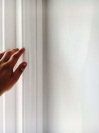 Close-up of human hand touching white wall