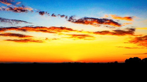 Silhouette landscape against dramatic sky during sunset