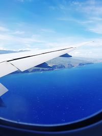 Airplane flying over sea against blue sky