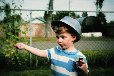 Close-up of boy standing against chainlink fence