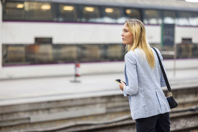 Businesswoman with blond hair waiting for train at station