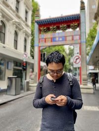 Portrait of young man sitting on street in city