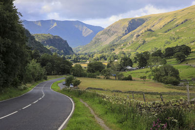 Scenic view of road by mountains against sky