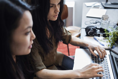 Close-up of businesswomen using laptop in creative office