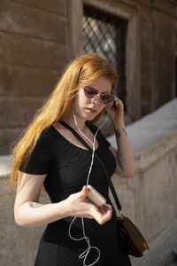 Gold hair girl listening music with smartphone using cabled earphones