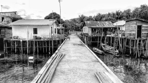 Walkway amidst houses and buildings against sky