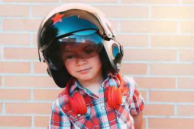 Portrait of boy with russian pilot's helmet on brick wall