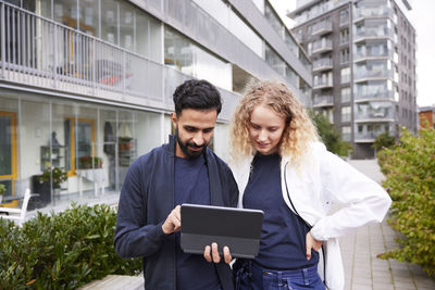 Male and female worker looking at tablet in courtyard