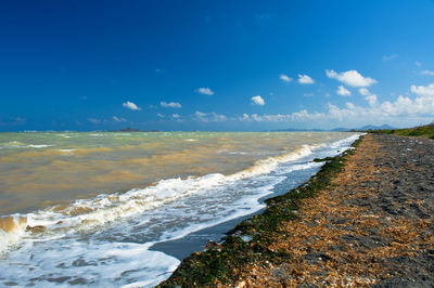 Scenic view of beach against blue sky