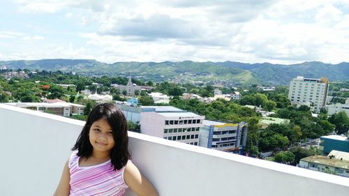 Portrait of young woman against buildings