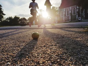 Low section of boy playing with ball against sky