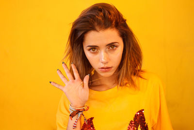 Portrait of young woman with brown hair against yellow background