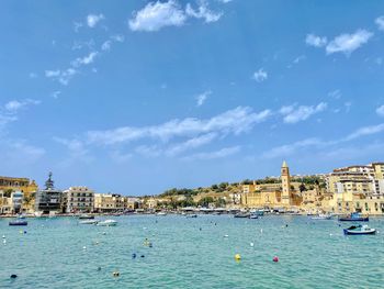 View of buildings by sea against cloudy sky