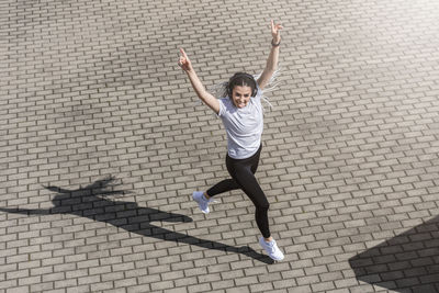 Full length portrait of boy jumping on cobblestone