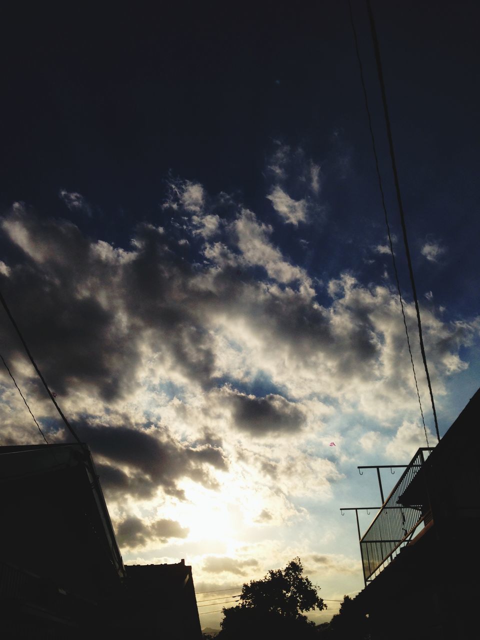 low angle view, architecture, built structure, building exterior, sky, silhouette, cloud - sky, sunset, building, cloud, cloudy, high section, city, outdoors, street light, residential structure, house, residential building, dusk, power line