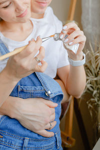 Midsection of woman applying nail polish