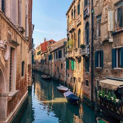 Boats moored in canal amidst buildings in city