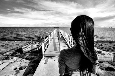 Rear view of woman looking at sea shore against sky